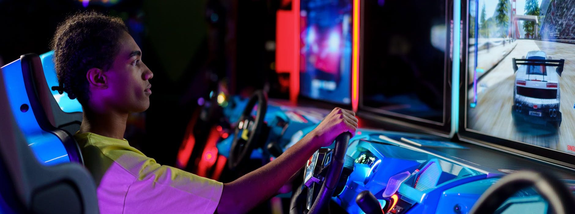 man playing car racing arcade machine