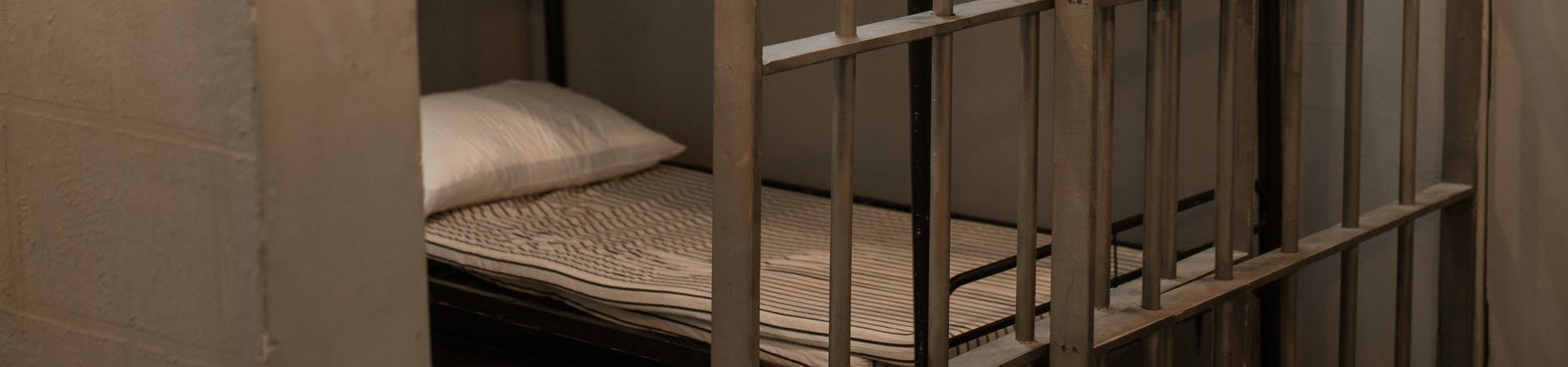 a bunk bed with striped linen behind bars